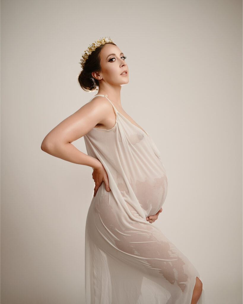 studio maternity photographer in augusta ga portrait of a pregnant woman holding her belly holding a white dress